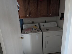 A laundry room with two washing machines, wooden cabinets above, and a door with a brass handle. - Charming 2-bedroom condo with view in beautiful Flagstaff (Flagstaff)