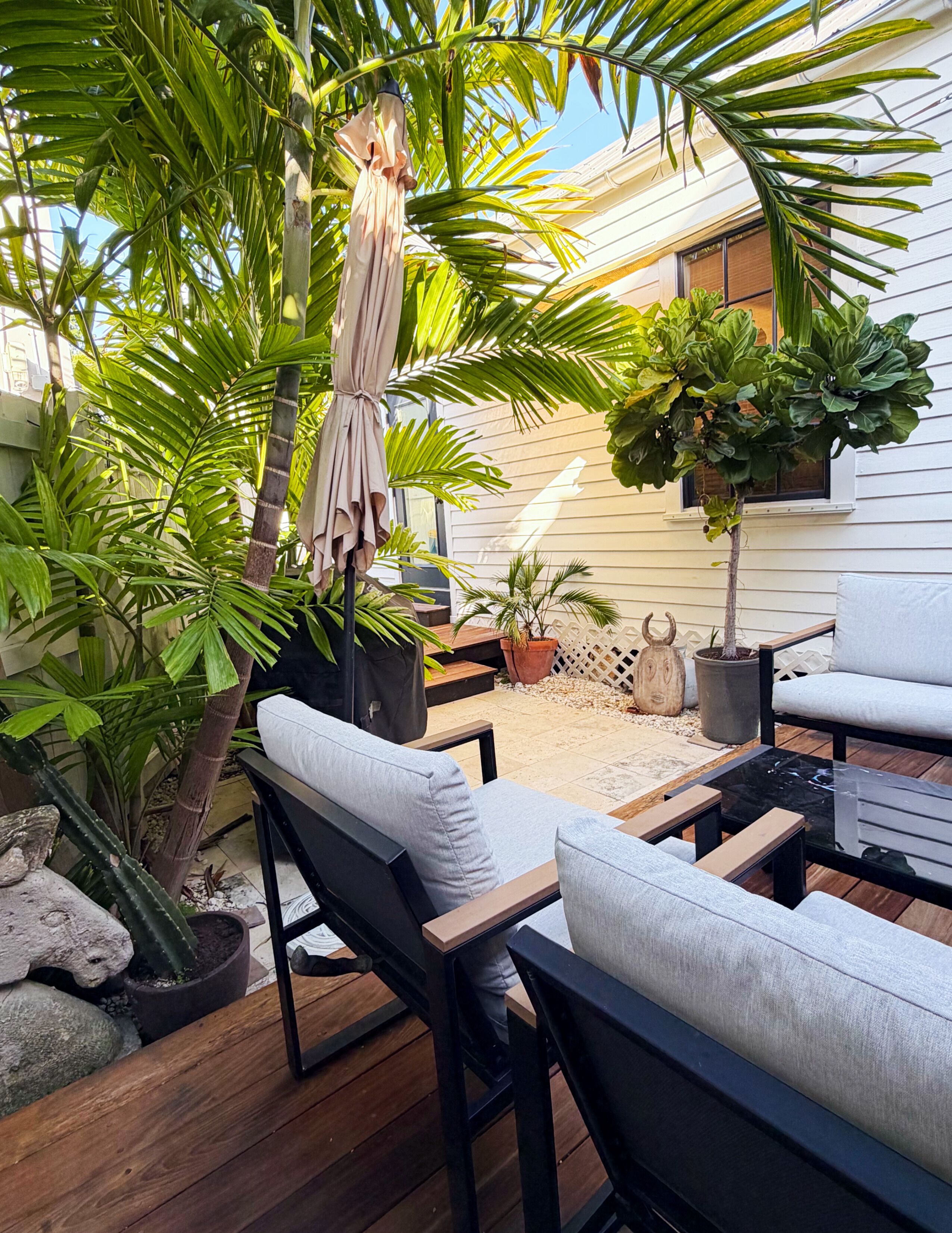 A patio with outdoor furniture, a hanging umbrella, and various potted plants.