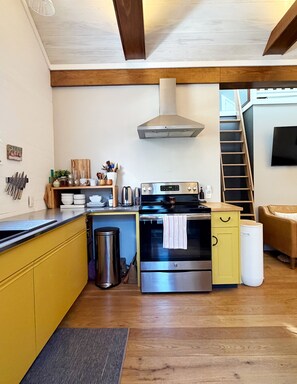Una cocina moderna con armarios amarillos, electrodomésticos de acero inoxidable y techo de madera.