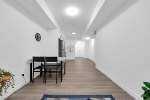 A modern interior with a dining area, kitchen, and a hallway leading to a door. - 3BHK Close to Downtown/Whyte Ave/UOFA (Edmonton)