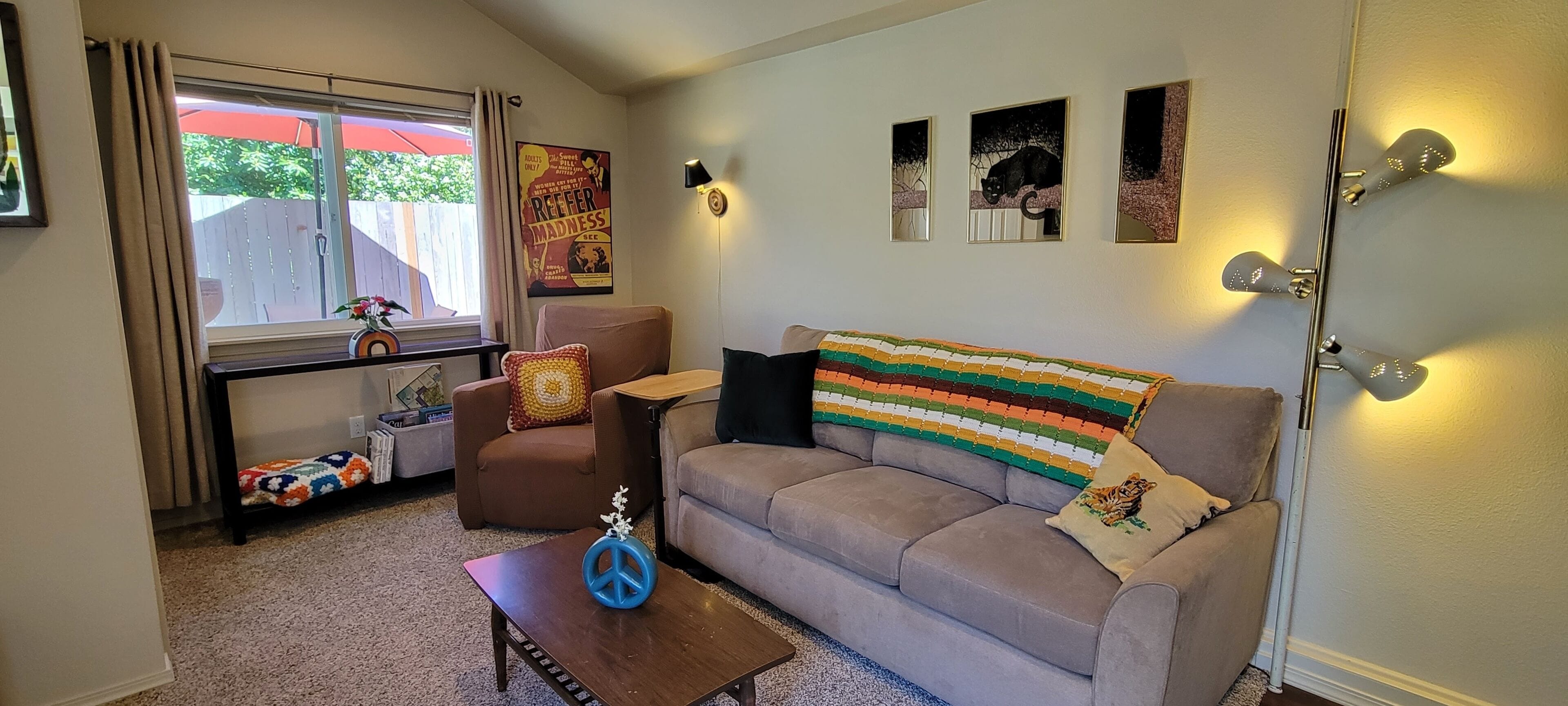 A living room with a sofa, a coffee table, a chair, and a window with curtains.
