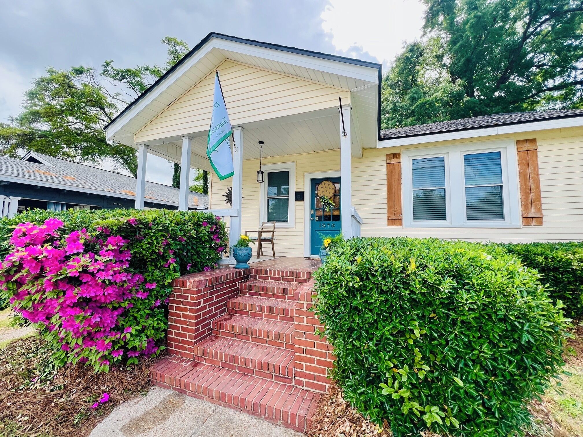 A residential house with a front porch, steps leading to the door, and a mailbox.