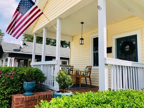 Eine Veranda mit einer Flagge, einem Tisch mit Stühlen und Blumentöpfen.