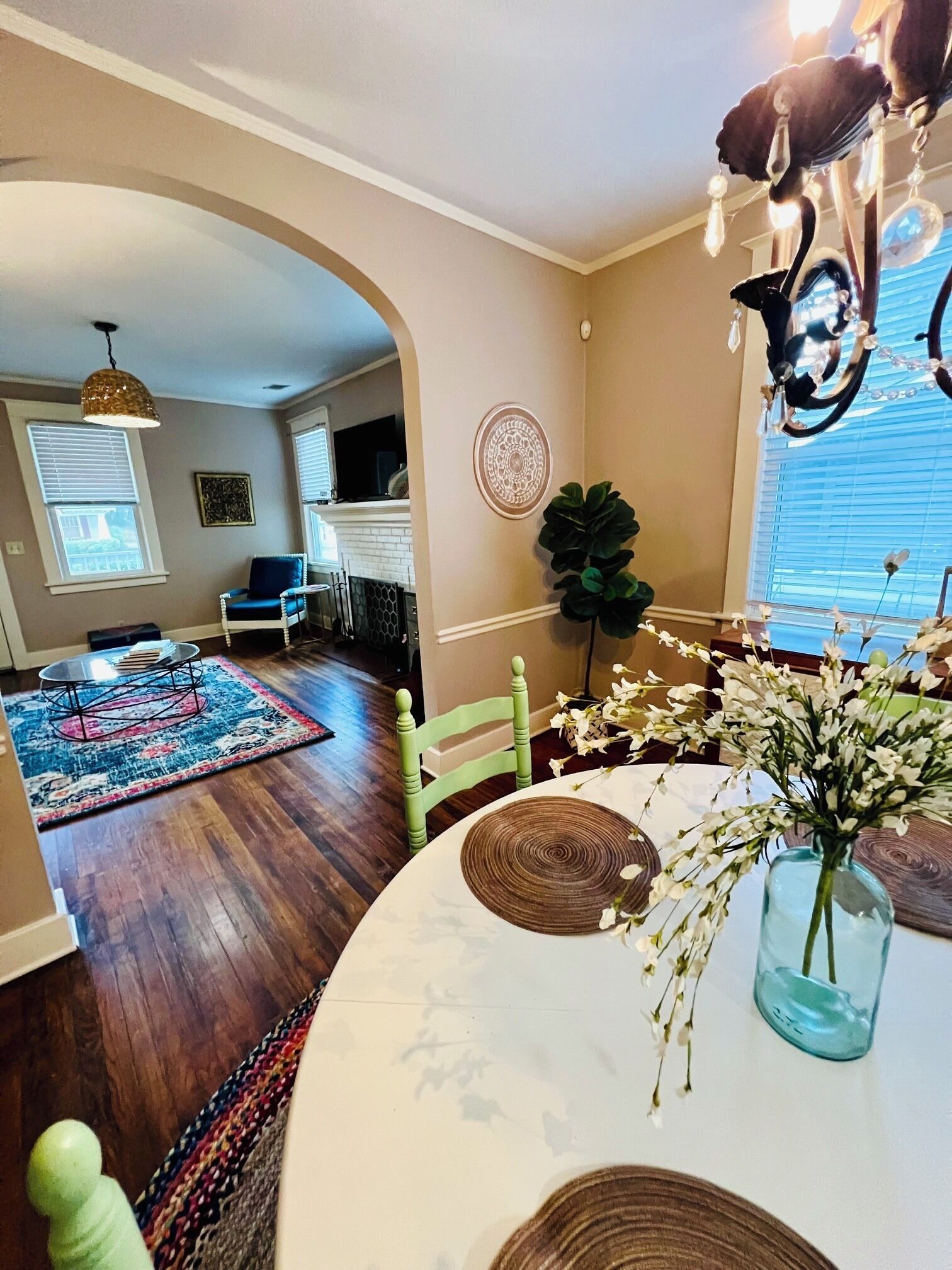 A living room with a dining table, a chandelier, and a view of the adjacent kitchen.