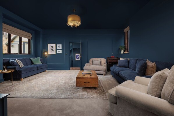 A living room with a blue wall, two sofas, a coffee table, and a chandelier.