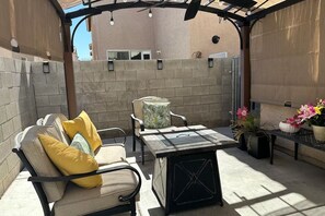 Eine Terrasse im Freien mit einer gepolsterten Sitzecke, einem kleinen Tisch und Topfpflanzen.