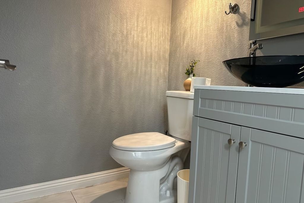 A bathroom with a toilet, a sink, and a cabinet.