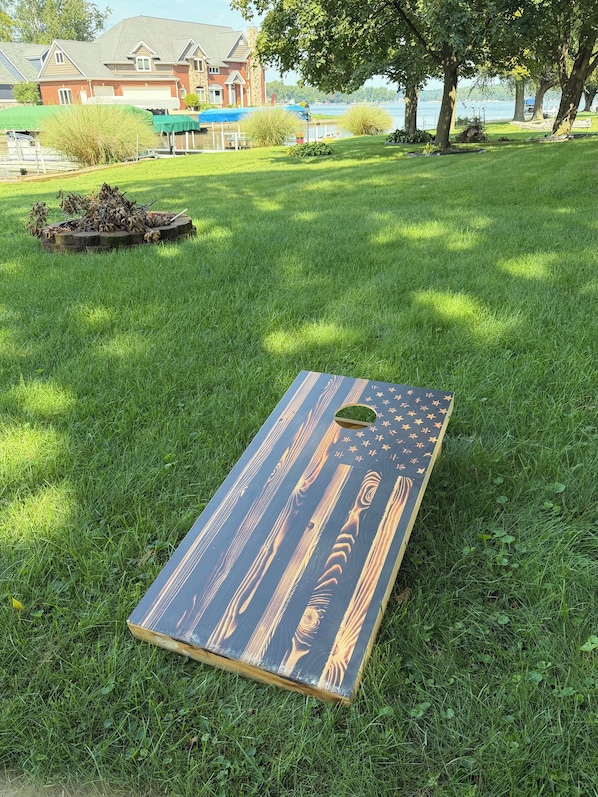 A flat surface with a pattern of stars and stripes, possibly a table or board, on a grassy area with trees and a building in the background.