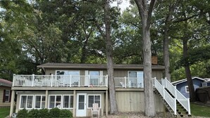 A two-story house with a balcony, a front door, and a staircase leading to the upper level.