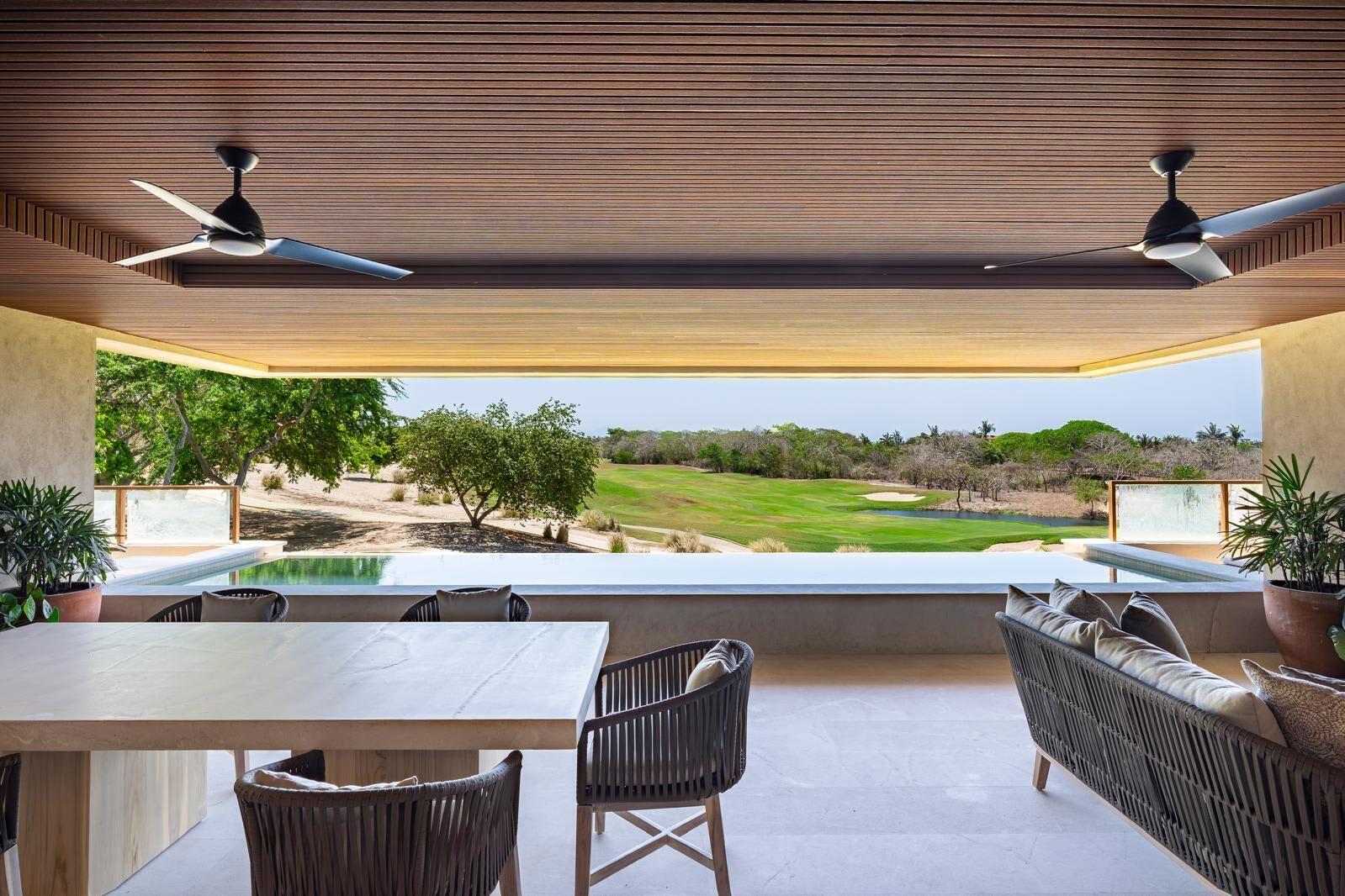 A modern outdoor dining area with a view of a golf course.