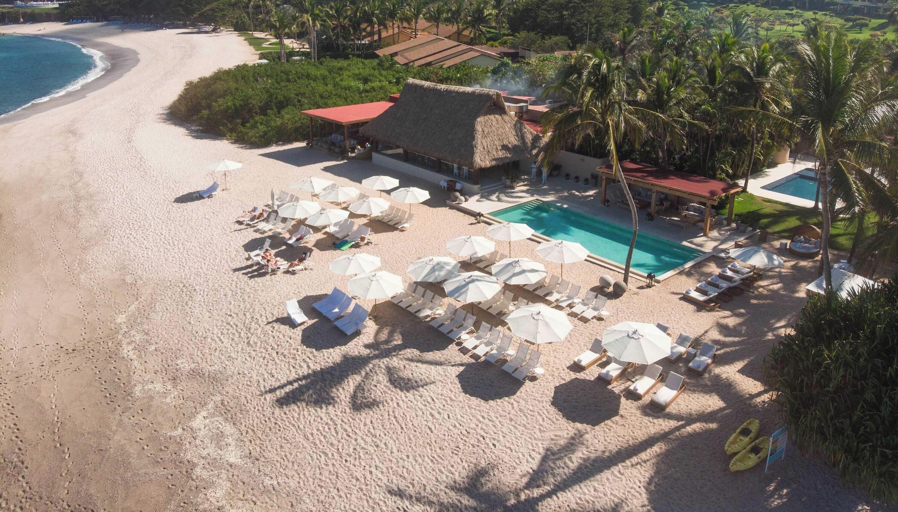 Ein Strandresort mit Pool, Liegestühlen und Sonnenschirmen.