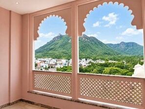 Una habitación con vista a un paisaje montañoso a través de una ventana con diseño de celosía.