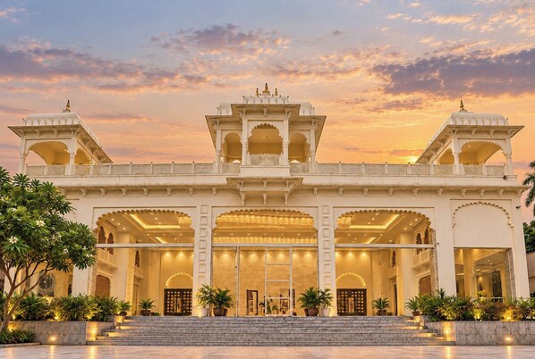 A grand building with multiple arches and a central entrance, surrounded by well-maintained gardens.
