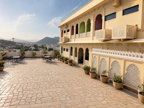A courtyard with a tiled floor, potted plants, outdoor seating, and traditional architectural elements.