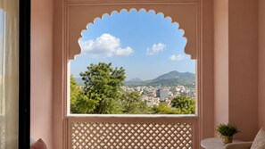 A room with a view of a cityscape through a decorative window with a lattice design.