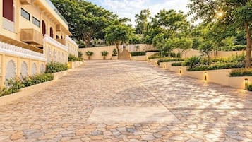 Un patio con un sendero de piedra que lleva a un edificio con ventanas arqueadas y un balcón.