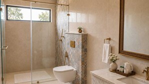 A modern bathroom with a glass shower enclosure, a white toilet, and a marble sink. - juSTa Luxe Monsoon Palace (Udaipur)