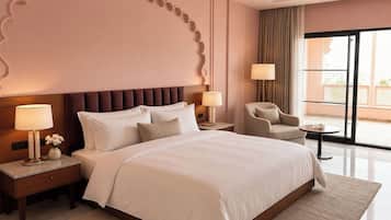 Una habitación de hotel con una cama grande, dos mesitas de noche con lámparas, una silla y vistas al exterior a través de un ventanal amplio.
