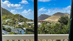 A view from a window overlooking a town with buildings, greenery, and mountains. - Island Heights (Orient Bay)