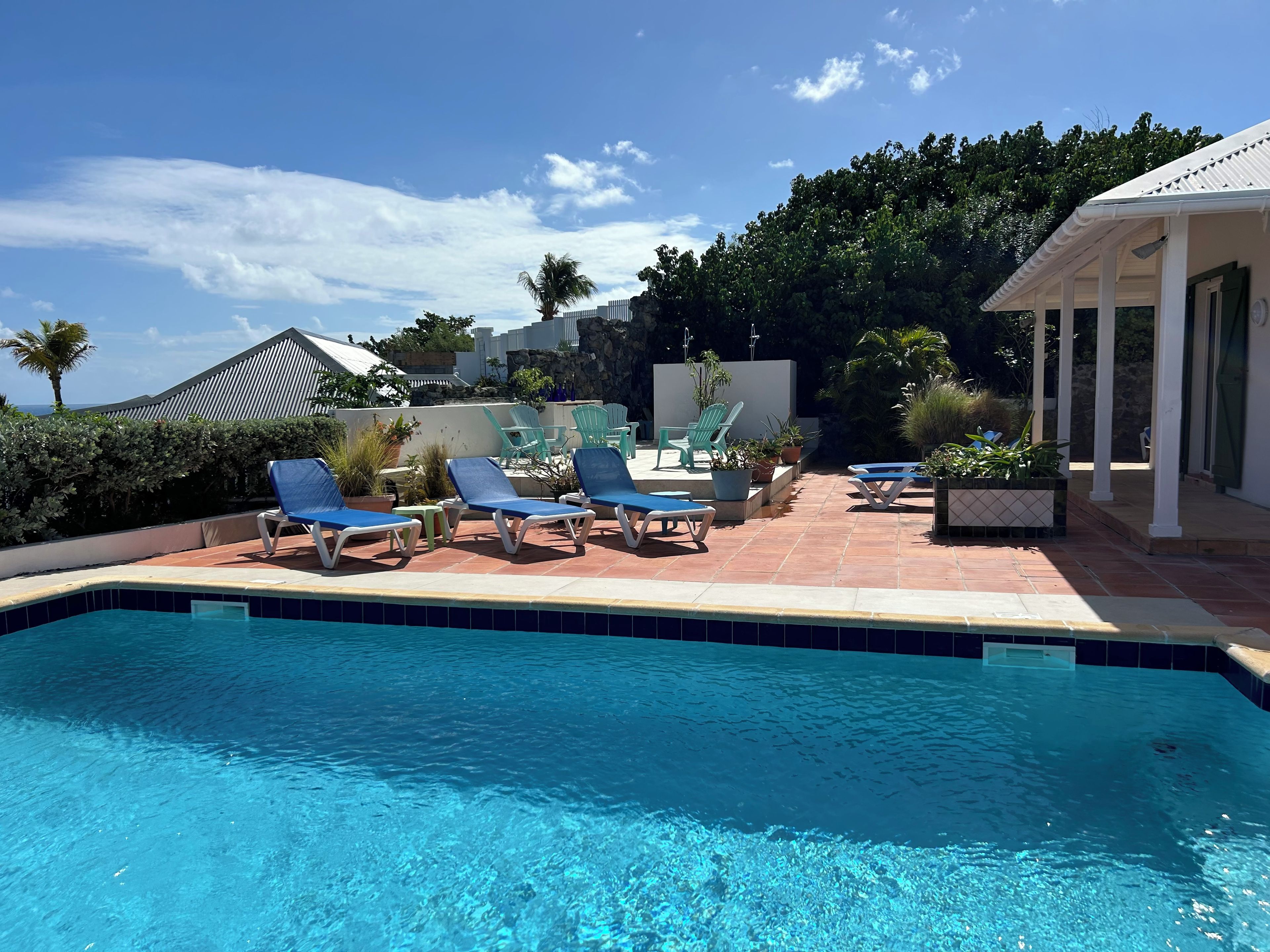 A swimming pool with lounge chairs and potted plants.