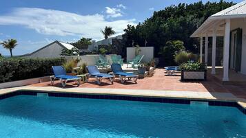 A swimming pool with lounge chairs and potted plants.