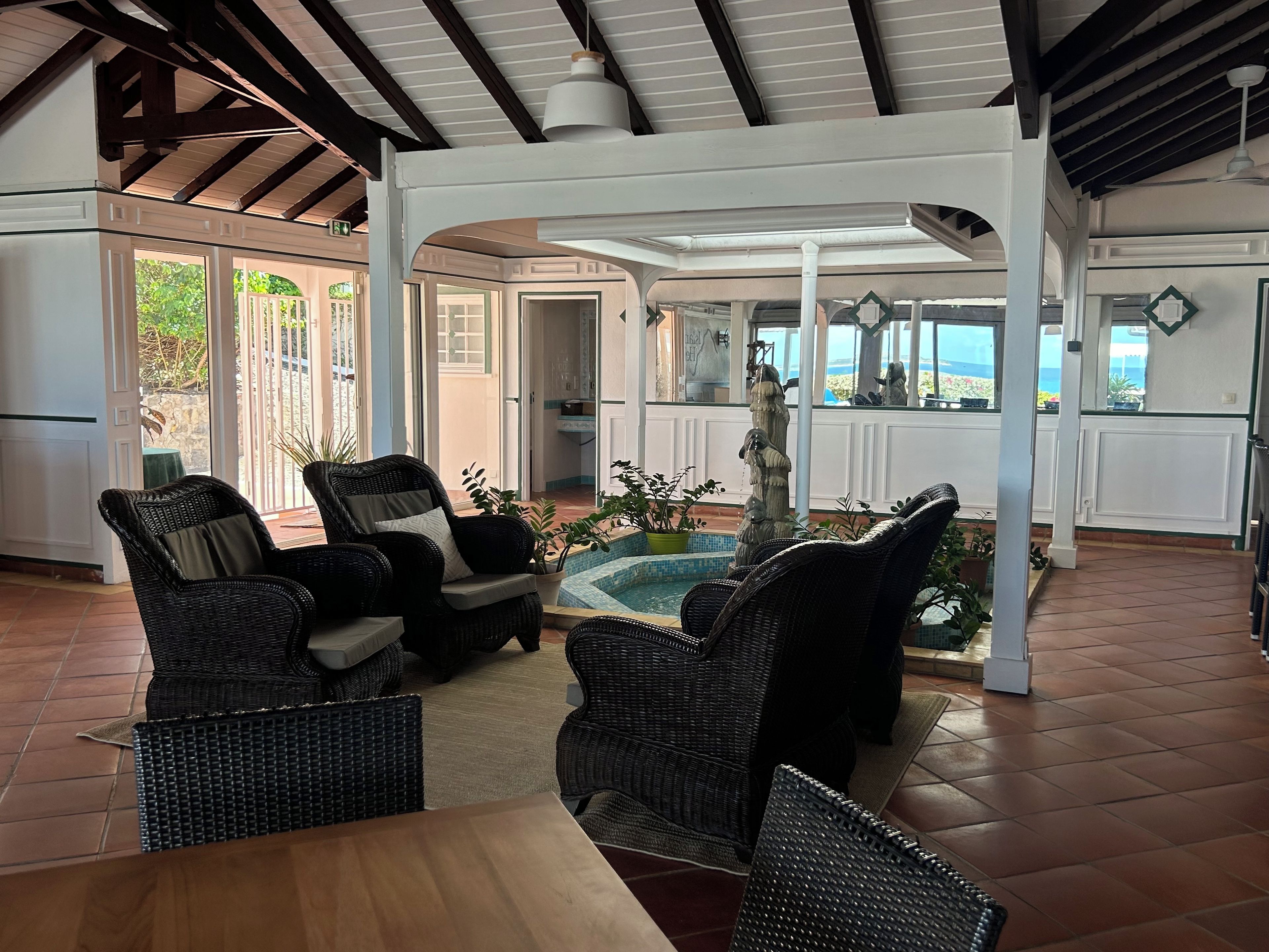 A covered outdoor seating area with wicker furniture and a central water feature.