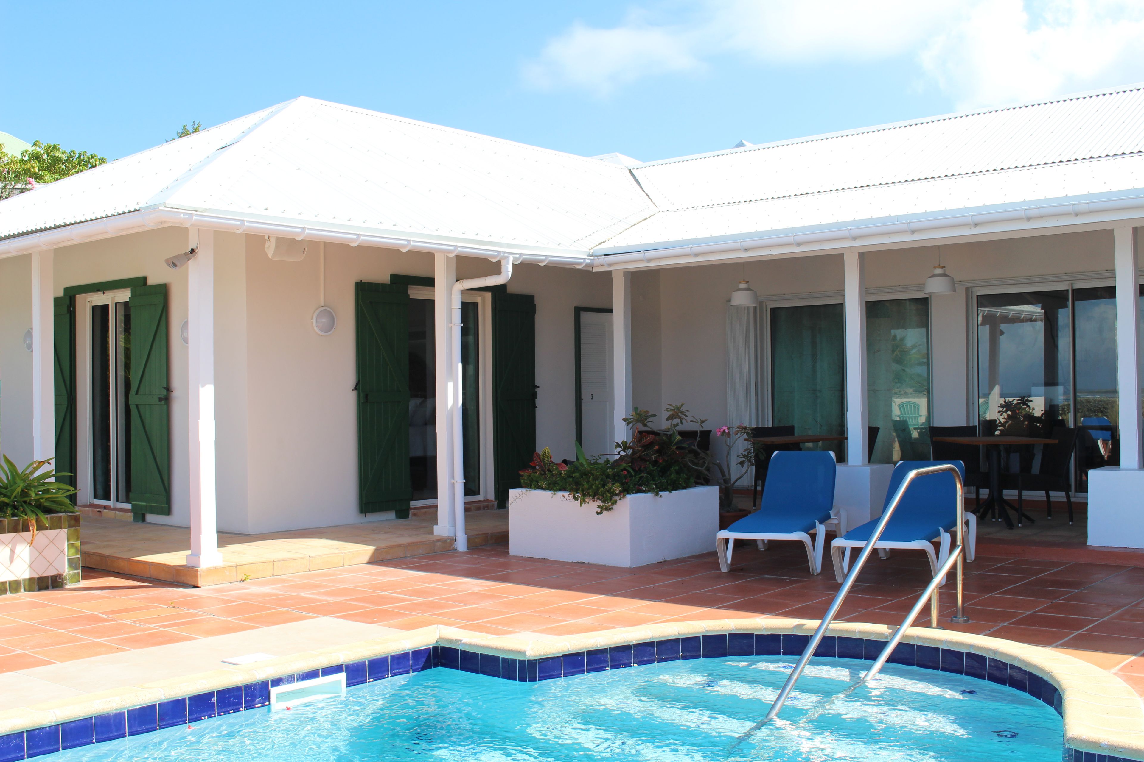 Un área junto a la piscina con un porche cubierto, una piscina y mobiliario exterior.