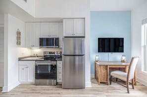 A modern kitchen with stainless steel appliances, white cabinetry, and a dining area with a wooden table and chairs.