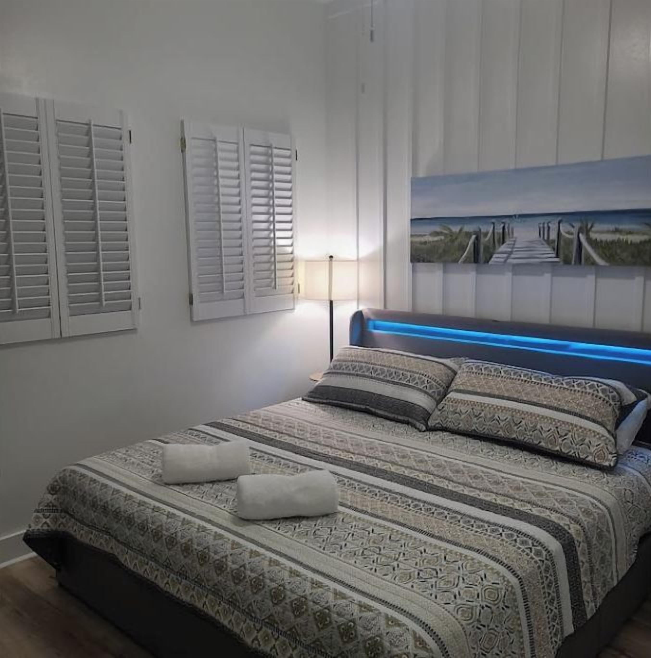 Een slaapkamer met een bed, een schilderij en een lamp.