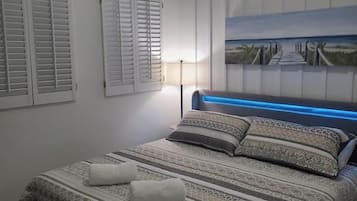 Een slaapkamer met een bed, een schilderij en een lamp.