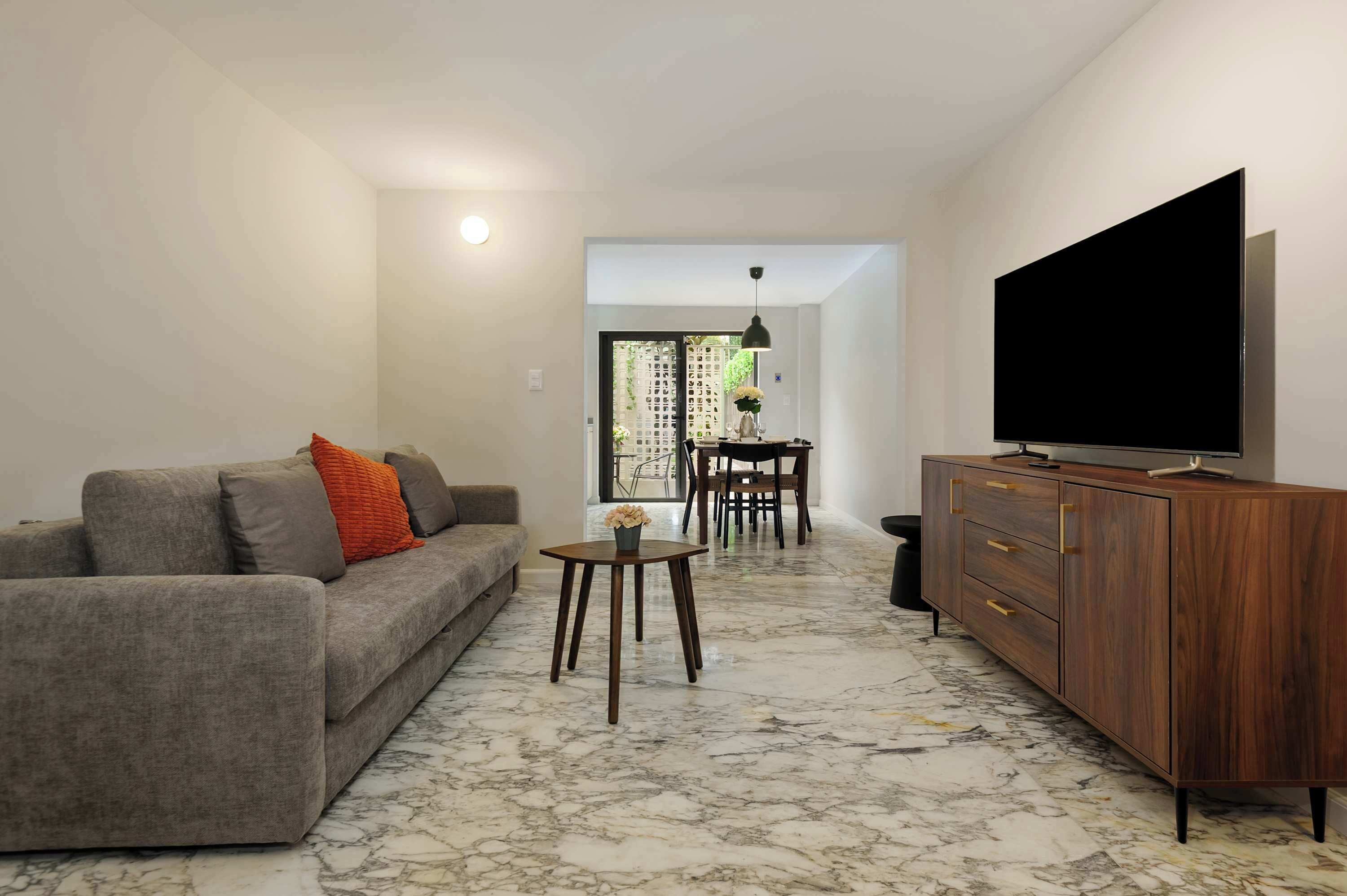 A living room with a sofa, a coffee table, a TV, and a wooden cabinet.