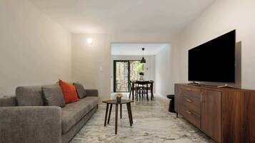 A living room with a sofa, a coffee table, a TV, and a wooden cabinet.