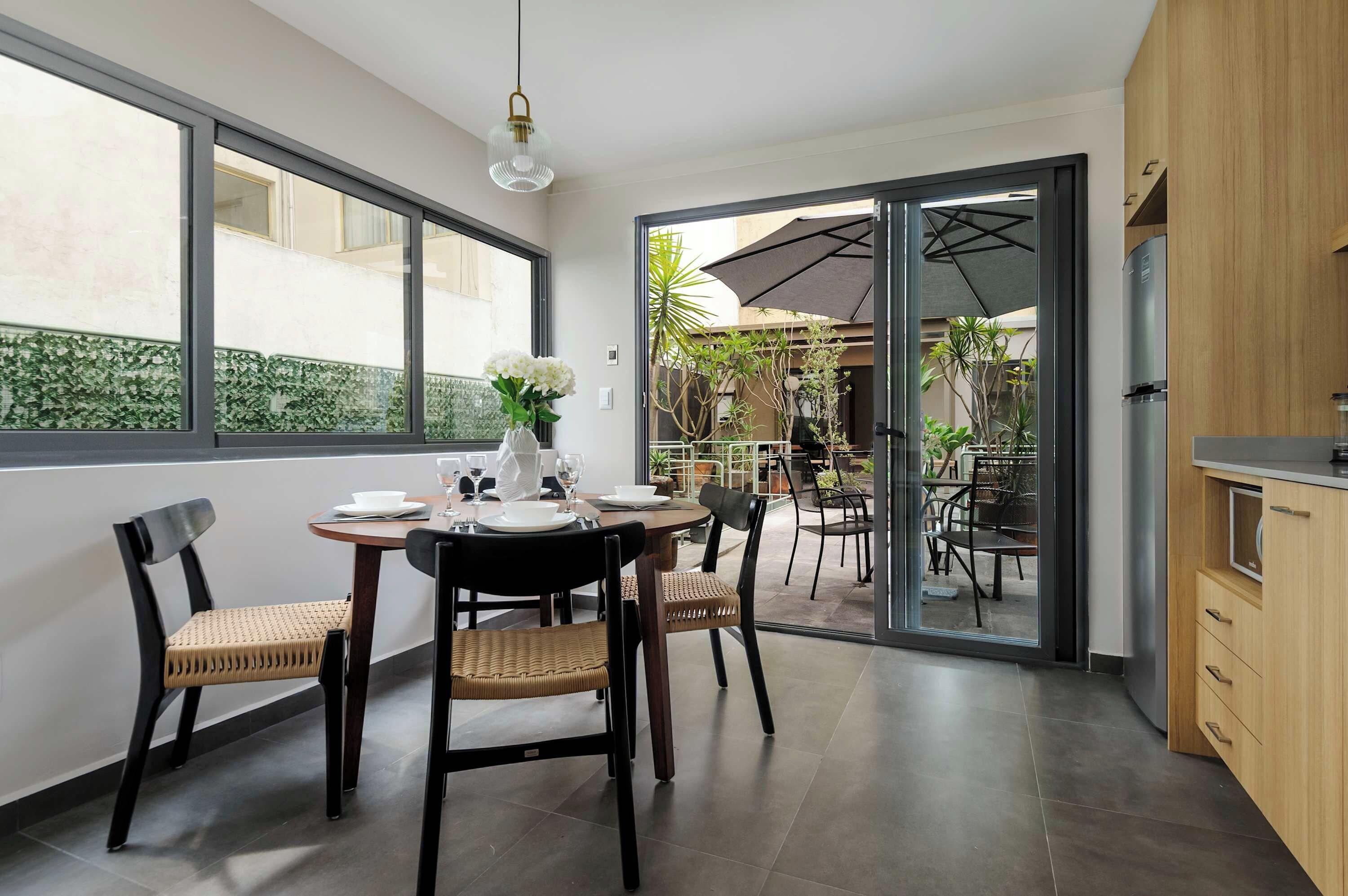 A dining area with a table set for four, chairs, and a vase of flowers.