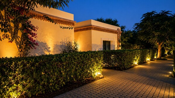 A pathway leading to a building with a tiled entrance and a door.