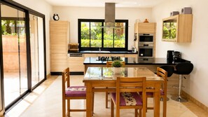 A modern kitchen with a dining table, chairs, and built-in appliances.