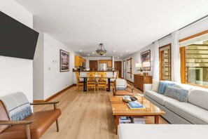 Ein modernes Wohnzimmer mit einer Couch, einem Couchtisch und einem Essbereich mit Stühlen sowie einer Küche im Hintergrund.