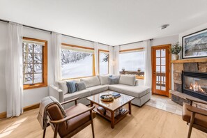 Ein gemütliches Wohnzimmer mit einer Eckcouch, einem Couchtisch und einem Kamin.