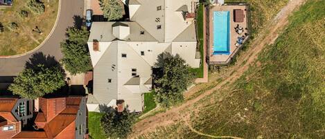 A residential area with a swimming pool, multiple houses, and a road.