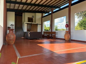 A covered outdoor area with a bench, a table, and two large vases. - Coffee farm 15 minutes from the coffee park (rural)