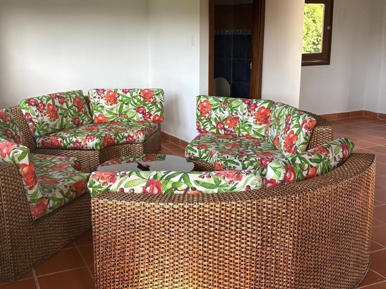 Un sofá modular de mimbre con tapicería floral en una habitación con suelo de baldosas.