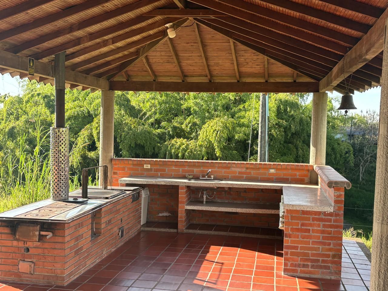 Een buitengebied met een barbecue, een bakstenen grill, een spoelbak en een overdekt dak.