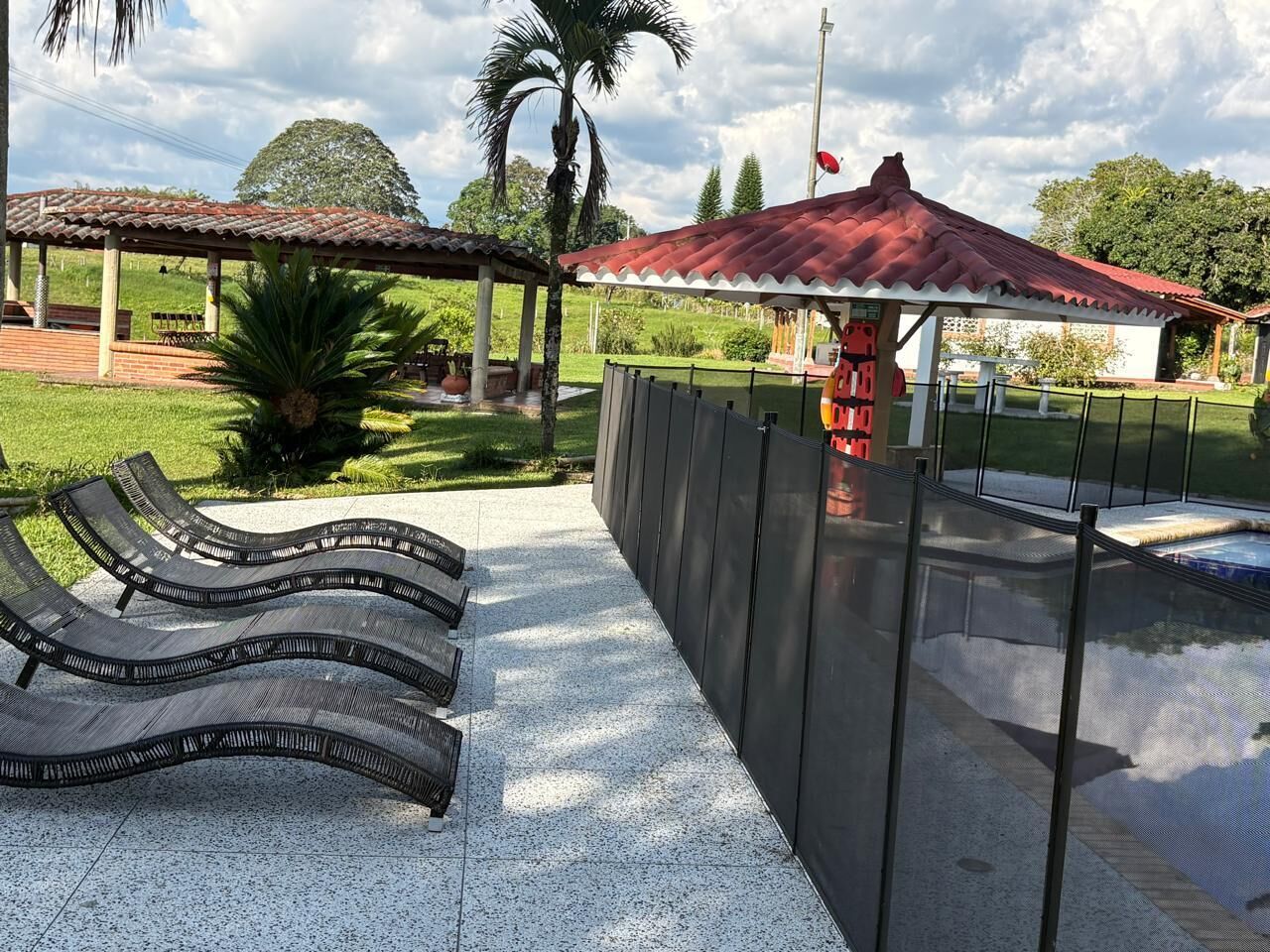 Espace extérieur aménagé avec une pergola et une zone couverte dotée d’un toit rouge.
