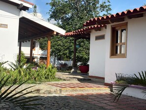 A courtyard with a tiled walkway, a covered seating area, and potted plants. - Coffee farm 15 minutes from the coffee park (rural)