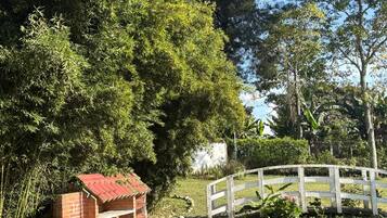 A brick structure with a red roof, a white fence, and a grassy area with trees.