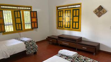 A room with two beds, a wooden dresser, and a wall-mounted television.