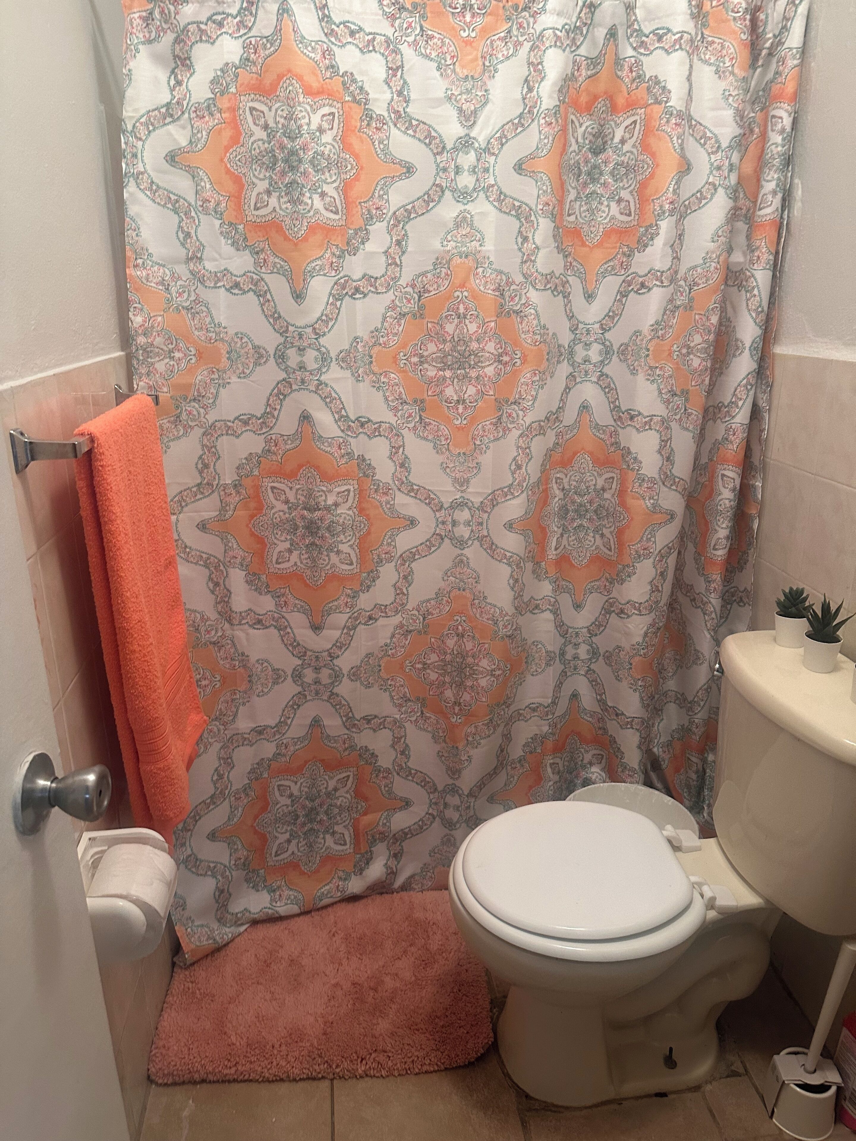 Un baño con cortina de ducha estampada, inodoro y toallero.