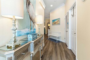 A hallway with a wooden floor, a bench, a painting, and a door. - Luxury Golf Cart & View, Steps to Beach,Pool,Tram (Miramar Beach)