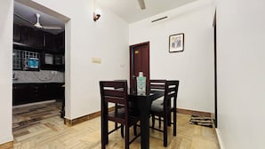 Een eethoek met een tafel en stoelen, een plafondventilator en een keuken in de achtergrond.