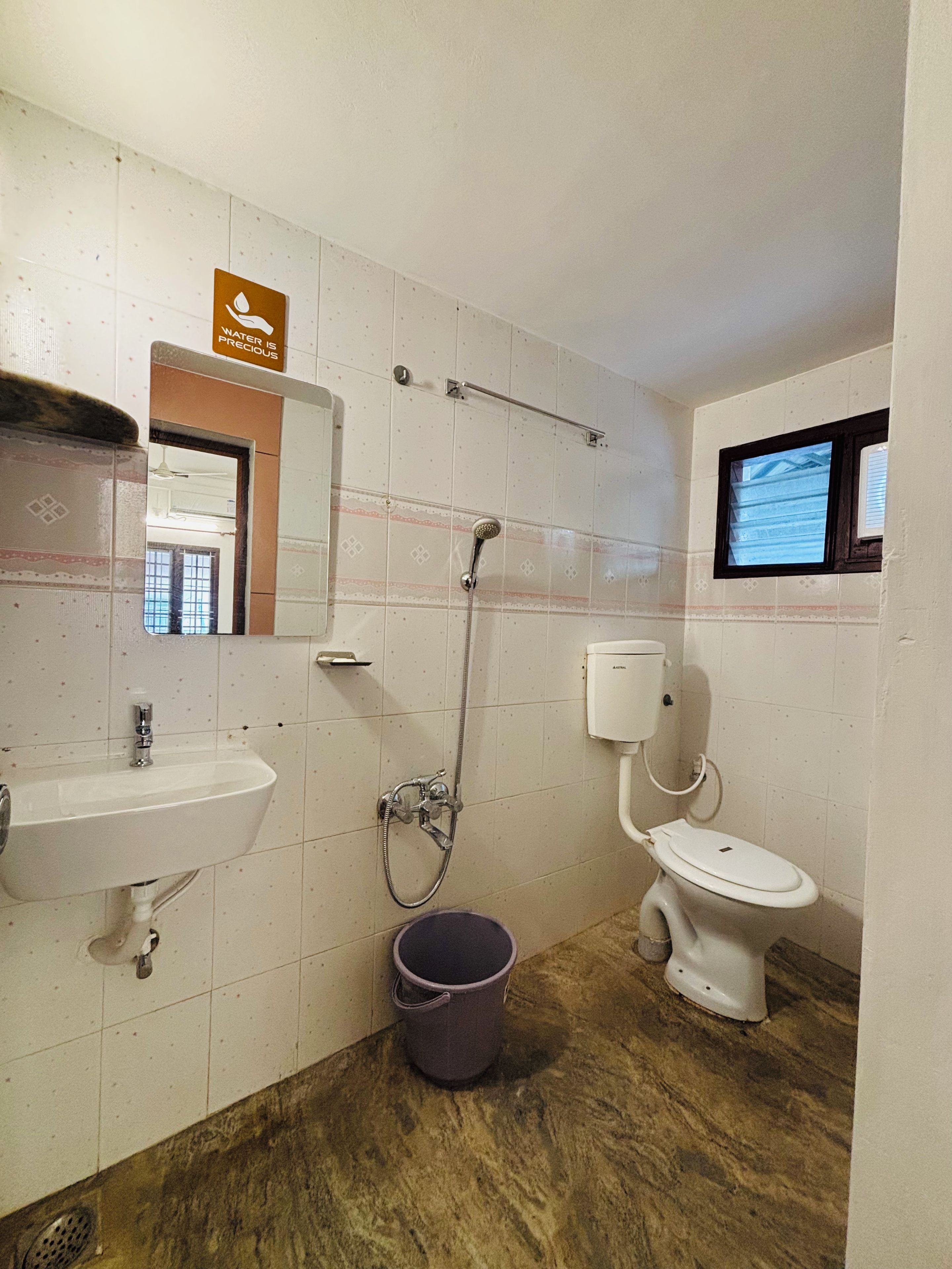 Un baño con lavamanos, inodoro, ducha y un cubo.