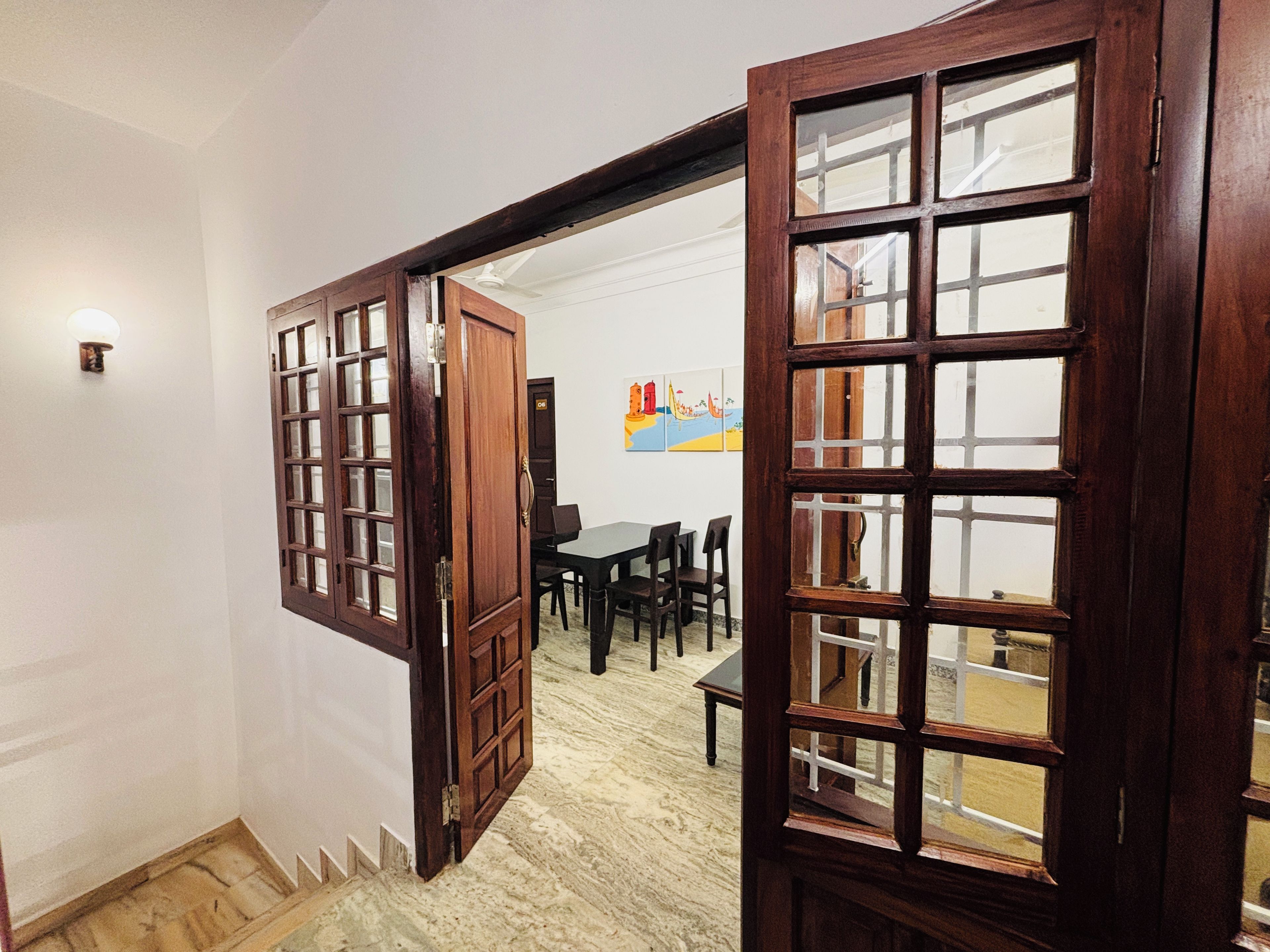 A room with a wooden door leading to a dining area with a table and chairs.
